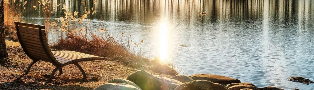 A quiet bench beside a sunlit lake, from Clara’s Finding a Healing Place website